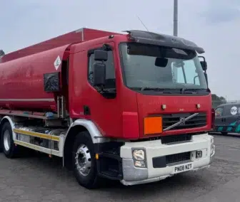 Red tanker truck parked in industrial area.